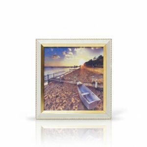 Square Framed Beach Sunset Art print with a rowboat on the sand, framed in a light color with a gold braided inner border.